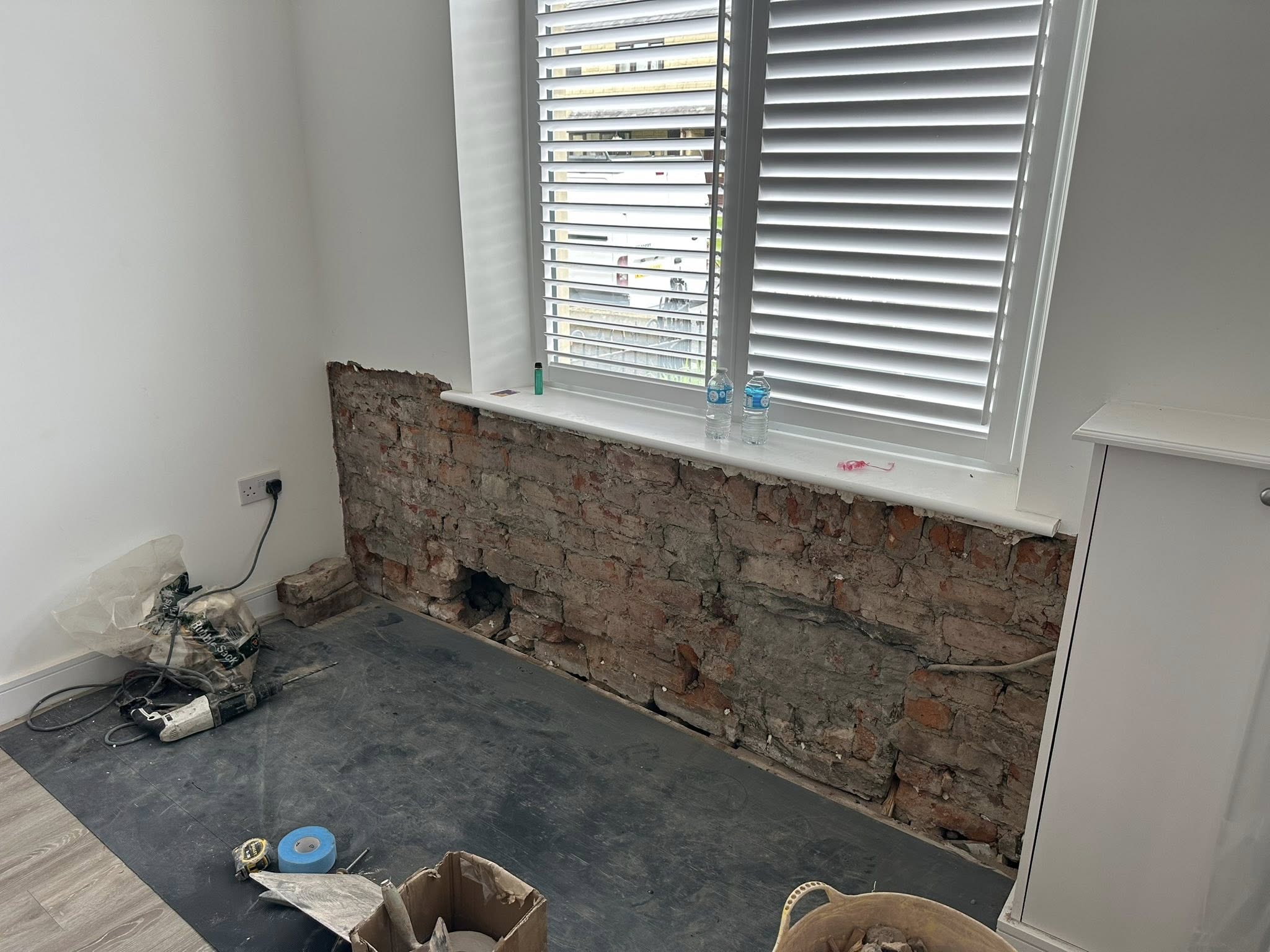 Exposed brick wall renovation showing bare plaster